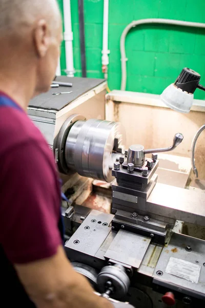 工場の生産部門で泡立て器で作業する機械オペレータの背面図 — ストック写真