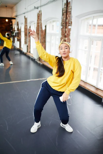 背景に大きな鏡を持つヘッドフォンで音楽を通してスタジオでアクティブな若いダンサーのトレーニング — ストック写真