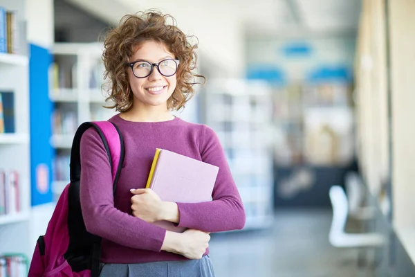 꿈꾸는 매력적인 여학생 안경에 포용하고 도서관에 서있는 — 스톡 사진