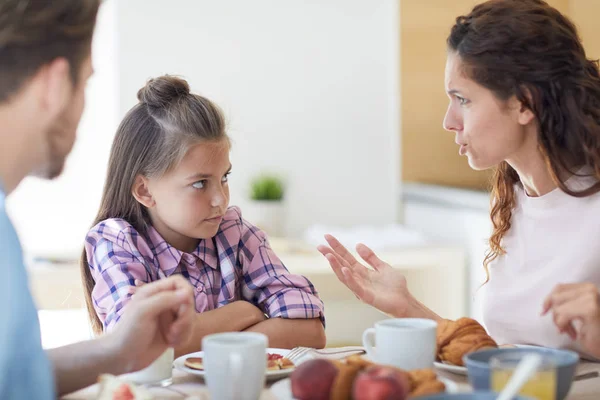 年轻而不满意的母亲在厨房吃早饭时和她的小女儿说话 — 图库照片