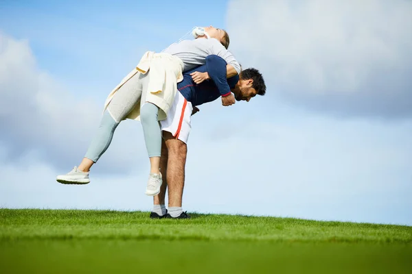 Young Sportsman Lifting His Girlfriend Back While Leaning Green Field — Stock Photo, Image