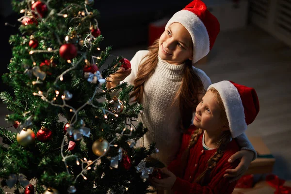 Twee Kleine Zusters Santa Caps Kijken Naar Versierde Kerstboom Heilige — Stockfoto