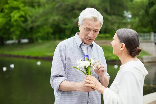 带着一束鲜花的老人在户外对妻子说白色的 — 图库照片