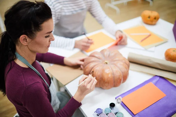 Ernste Konzentrierte Künstlerin Schürze Sitzt Tisch Und Bemalt Kürbis Kunstatelier — Stockfoto