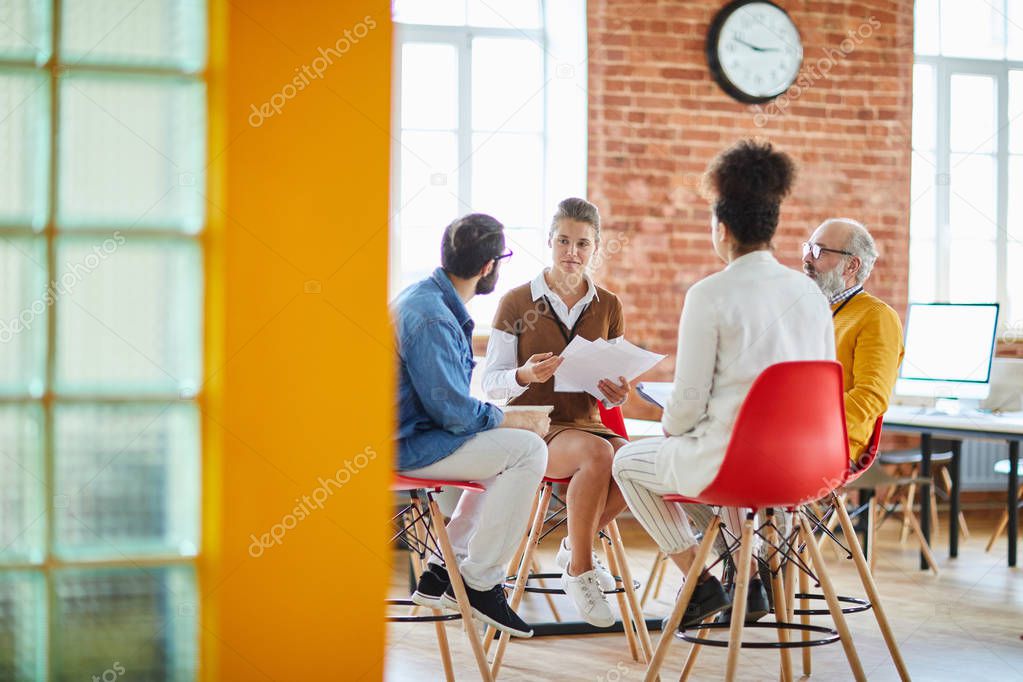 Several colleagues sitting in circle during business discussion or consultation about features of modern company