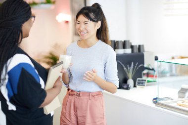 İki genç neşeli öğrenci dersten sonra kafeteryada içki içerken üniversite haberlerini tartışıyor