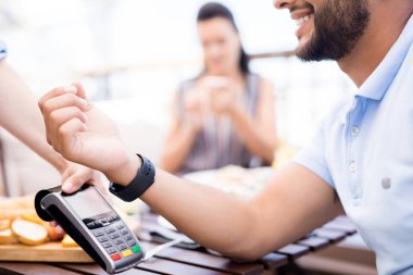 Akıllı, genç ve modern bir adam öğle yemeğinden sonra kafede elektronik makineden ödeme yapıyor.
