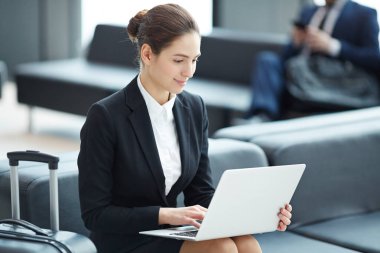 Mutlu genç analist veya dizüstü bilgisayar ile borsa aracısı havaalanı salonunda online veri bakarak