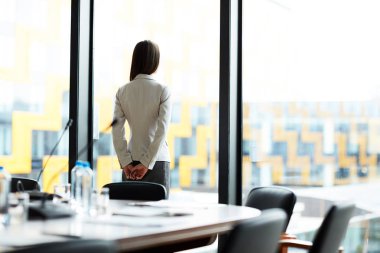 Konferans odasında pencerenin yanında duran zarif iş kadınının arka görünüm portresi, kopya alanı