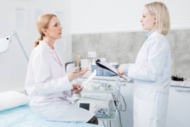 Toplantıda yeni ilaç veya tıbbi tedavinin etkinliğini tartışan beyaz ceketli iki tıp uzmanı