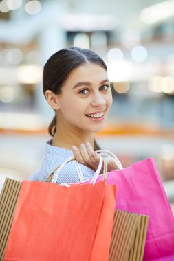Kamera önünde duran ve alışveriş merkezinde bakıyorsun paperbags grup ile şirin kız