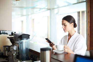 Çay ya da kahve barcounter spa Cafe tarafından ayakta ve mesajlaşma sahip genç kadın
