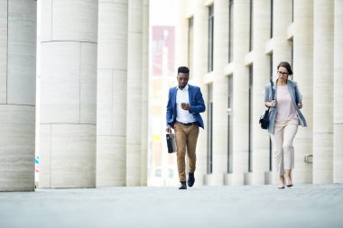 Ciddi yakışıklı siyah işadamı çalışan ve iş için geç kalırken telefonda mesaj kontrol, iş kadını çok acele