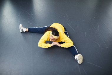 Uzatılmış bacaklar ile katta oturan ve egzersiz sırasında öne eğilerek genç aktif kadın genel bakış