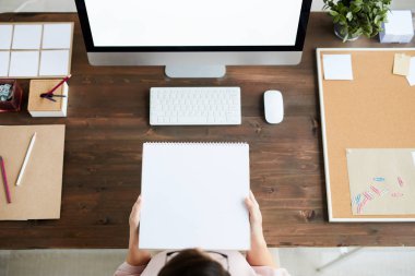 Bilgisayar ekranının önünde otururken boş bir sayfa ile not defteri tutan tasarımcı