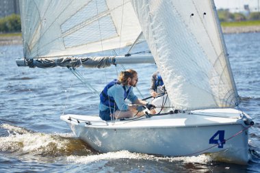 Ciddi yakışıklı profesyonel yatçı yardımcısı ile birlikte spor yarışmasına katılırken yelkenli doğrudan ip kullanarak