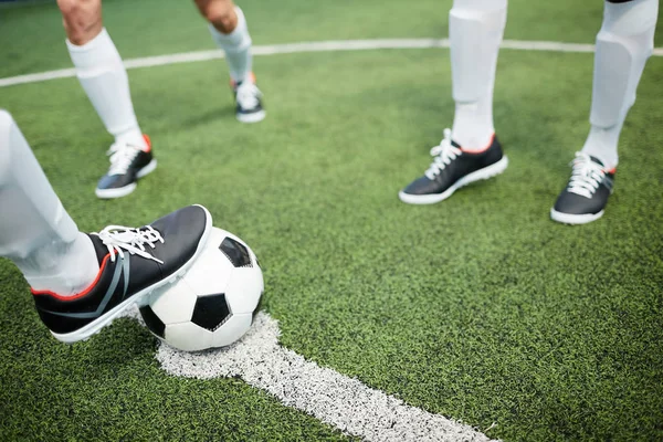 足球运动员的脚在球躺在足球场的白线与两个人附近 — 图库照片
