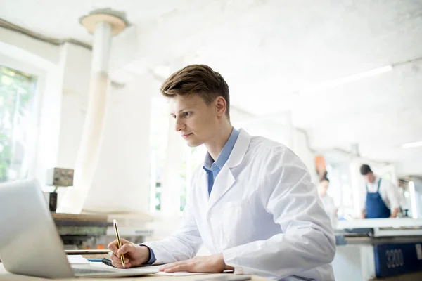 Jovem Whitecoat Lendo Dados Line Tela Laptop Colocando Suas Notas — Fotografia de Stock