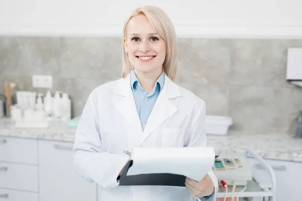 Young Smiling Woman Whitecoat Making Notes Paper Looking Camera Work — 스톡 사진