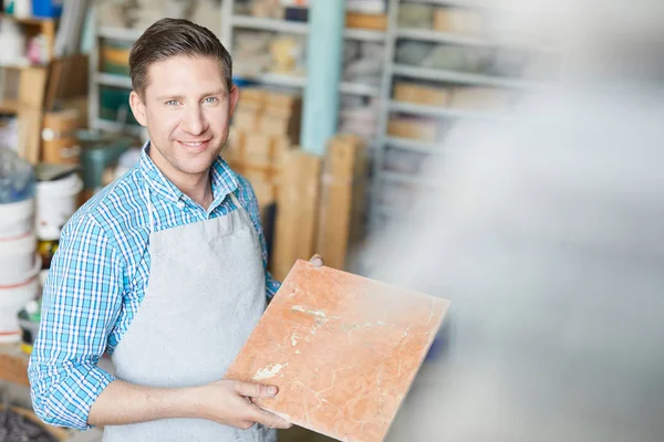 Cheerful Master Apron Showing Ceramic Square Tile Sample While Choosing — Stock Photo, Image