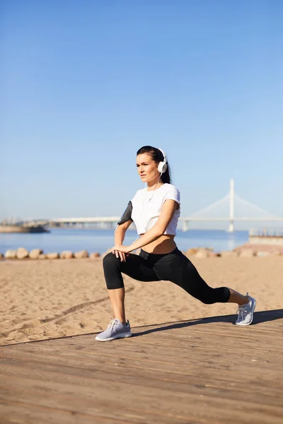 Allvarlig Attraktiv Ung Kvinna Hörlurar Gör Leg Stretching Efter Körs — Stockfoto