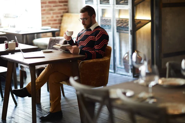 Ung Man Med Kopp Kaffe Läsa Bok Medan Spenderar Tid — Stockfoto