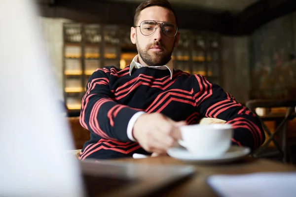 Серьезный Человек Пуловере Очках Сидит Столом Кафе Пьет Чай Кофе — стоковое фото