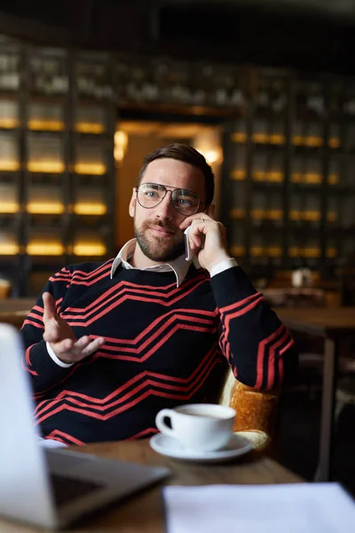 Młody Agent Ubraniach Casualwear Okularach Rozmawia Klientem Przez Smartfona Pijąc — Zdjęcie stockowe