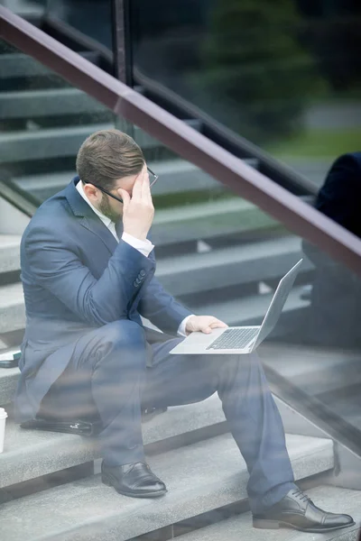 Stylowy Mężczyzna Sukni Biznesowej Okulary Patrząc Laptop Siedzi Aktówka Umieszczone — Zdjęcie stockowe