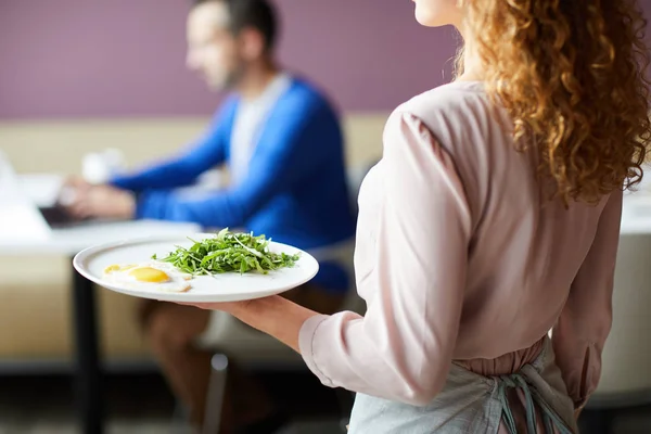 早餐期间 穿着粉红色上衣的女服务员带着煎蛋和绿色蔬菜向餐厅访客提供特写 — 图库照片