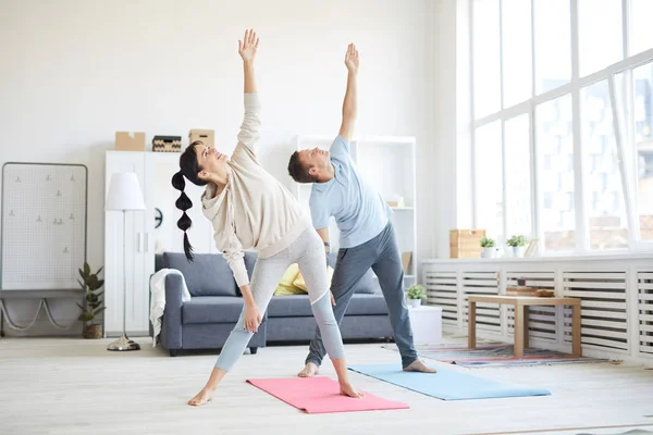 Giovane Coppia Sportiva Activewear Alzando Braccia Sinistre Durante Esercizio Soggiorno — Foto Stock