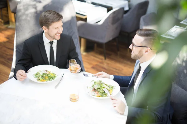两个年轻的商业伙伴坐在餐厅的餐桌旁 交谈和享受美味的食物 — 图库照片
