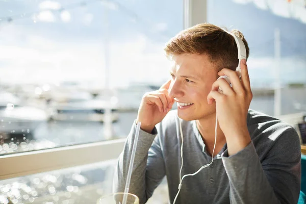 Joven Hombre Sonriente Auriculares Escuchando Música Mientras Mira Través Ventana —  Fotos de Stock