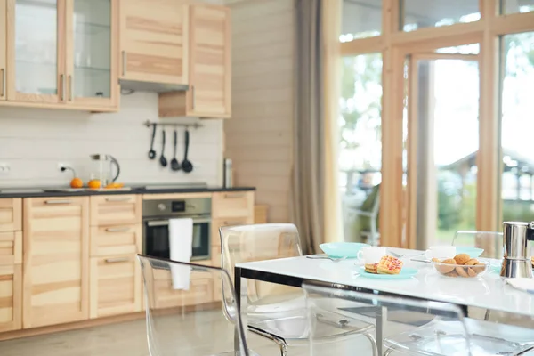 朝食と透明な椅子のためのモダンなテーブルセット 背景に木製のキッチンセットと空の国内キッチン — ストック写真