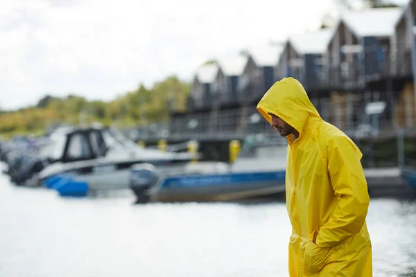 Poważny Smutny Młody Rybak Żółtym Wodoodpornym Płaszczu Trzymając Ręce Kieszeniach — Zdjęcie stockowe