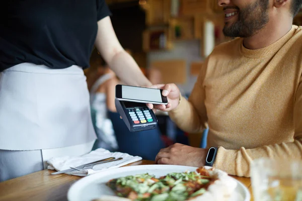现代咖啡馆的女服务员拿着支付机 而一个客户在午餐后进行非接触式付款 — 图库照片