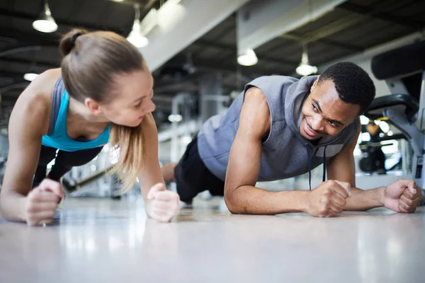 Young Intercultural Active Couple Doing Plank While Looking One Another — Stock Photo, Image