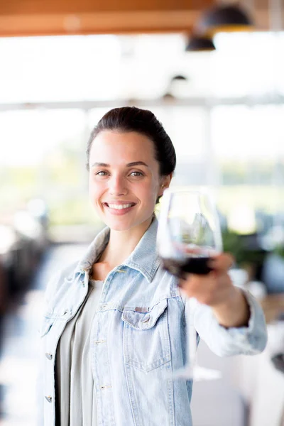 赤ワインのグラスを持つ若い陽気な女性は カメラを見ながら あなたと乾杯 — ストック写真