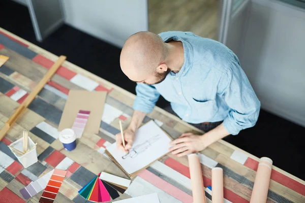 严肃的男性创意时装设计师在蓝色衬衫站在桌子上与彩色色板和纸张 并在工作室制作新的礼服草图 — 图库照片