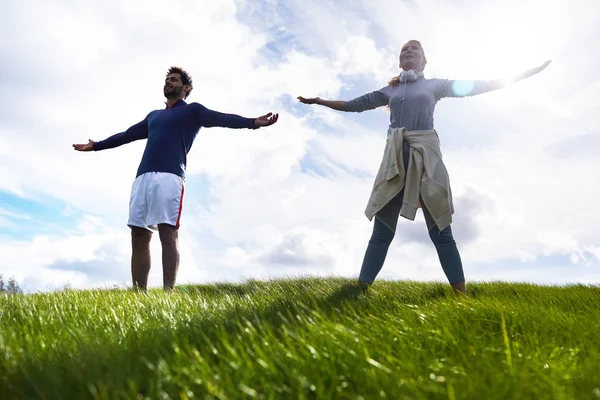 Young Couple Activewear Standing Green Field Arms Outstretched — Stock Photo, Image