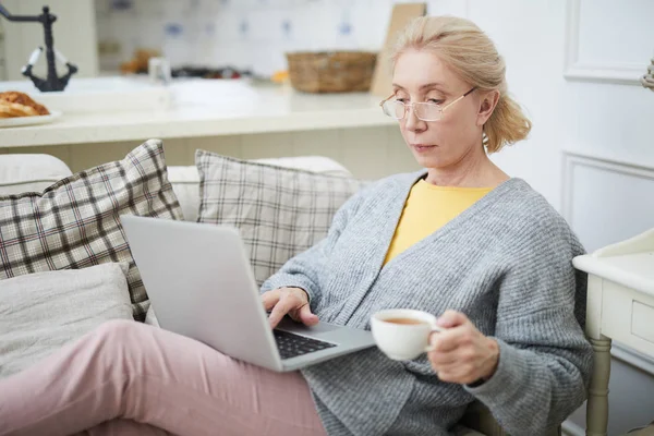 Mujer Edad Tranquila Con Portátil Taza Sentado Sofá Creación Redes —  Fotos de Stock