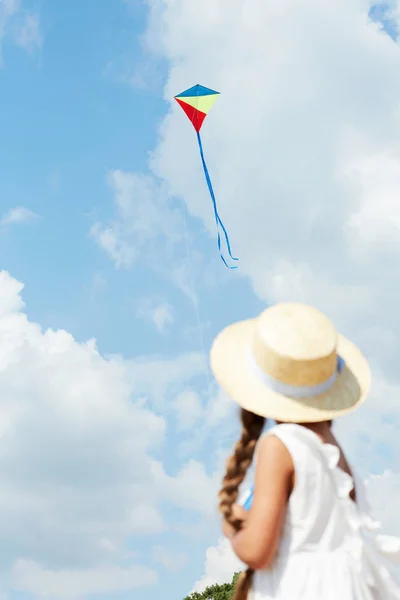 晴れた夏の日に凧遊びをする麦わら帽子をかぶった少女のバックビューポート コピースペース — ストック写真