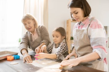 Mutfak masası tarafından ayakta kadın grubu ve kesiciler kullanırken ev yapımı kurabiye yapma