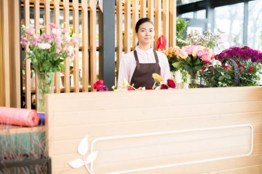 Genç dostu çiçekçi dükkanı Yardımcısı sayacı tarafından ayakta ve yeni müşteriler için servis önlük