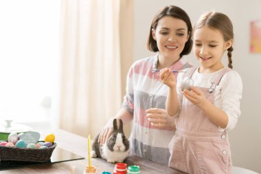 Tatil için hazırlanırken küçük kızı boyama yumurta bakarak sevimli Paskalya tavşan ile genç kadın