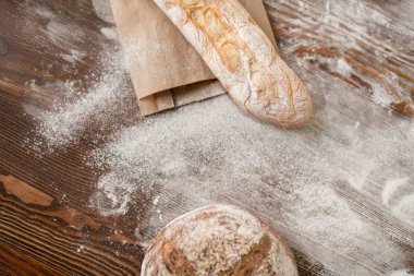 Ahşap masada iki çeşit taze ev yapımı pişmiş çavdar ve buğday ekmeği ve un