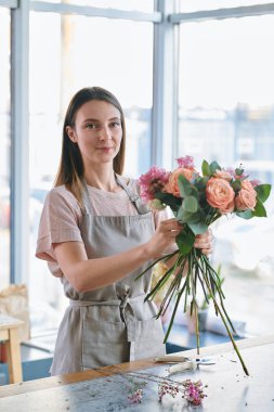 Güzel kız tarafından tablo kamera önünde duran ve demet gül mü yaparken bakıyorsun önlük