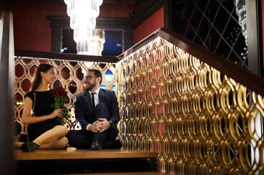 Şık kıyafetleri dekoratif içinde şık restoran korkuluk ve birbirlerine bakarak katta oturan mutlu genç tarihleri