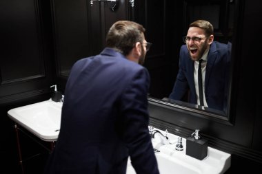 Ayna önünde, lavabo üzerinde bükme ve kendisi de bakarken çığlık iyi giyimli genç adam