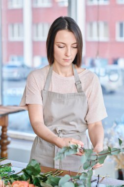 Genç ve güzel çiçekçi işyeri tarafından ayakta ve taze çiçekler grup sıralama iş giysisi